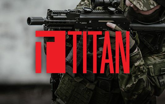 Camouflaged airsoft player aiming rifle with prominent red TITAN logo overlay representing titan airsoft batteries