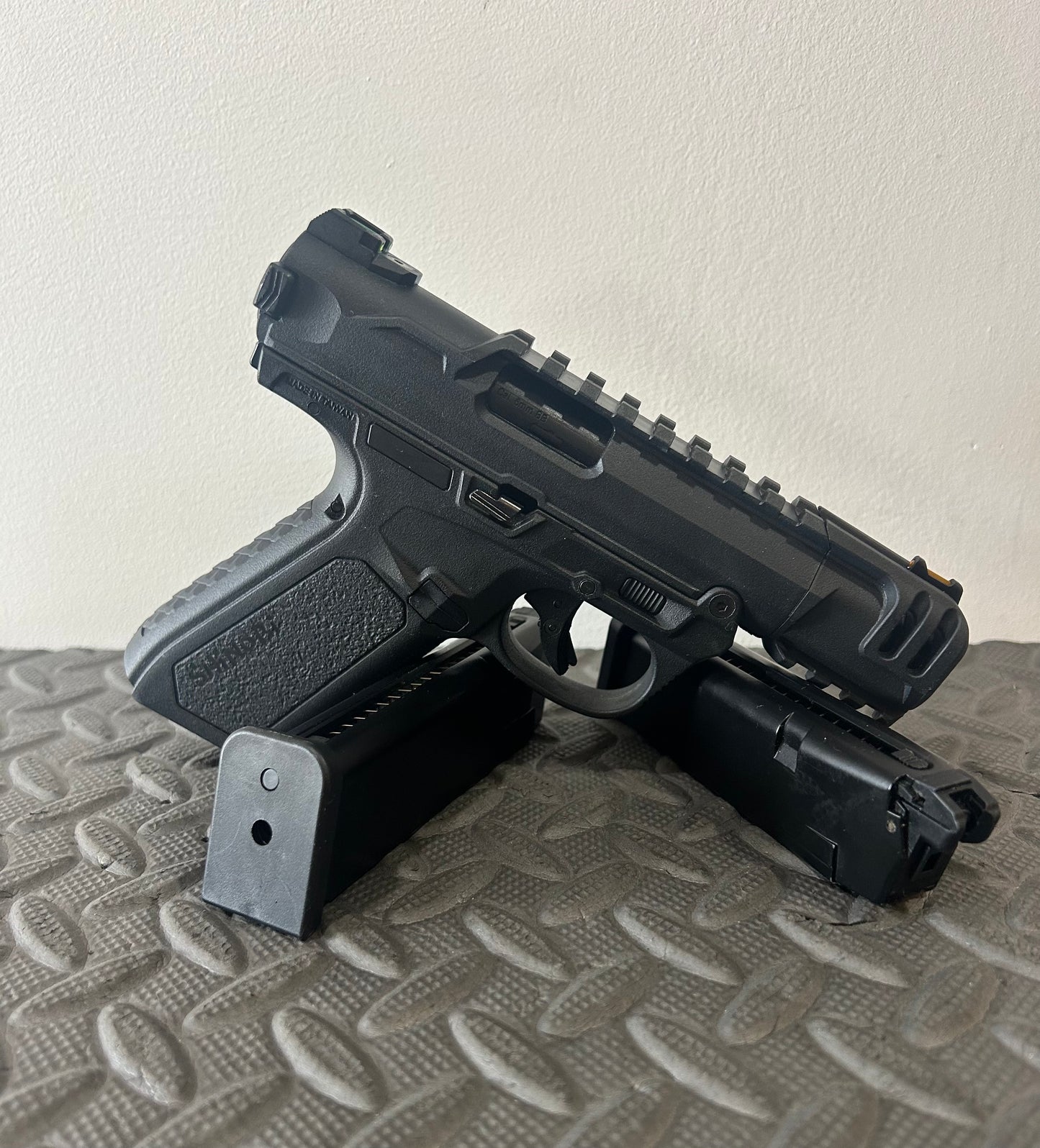 Black ACTION ARMY aap-01c assasin airsoft pistol with two magazines on textured surface
