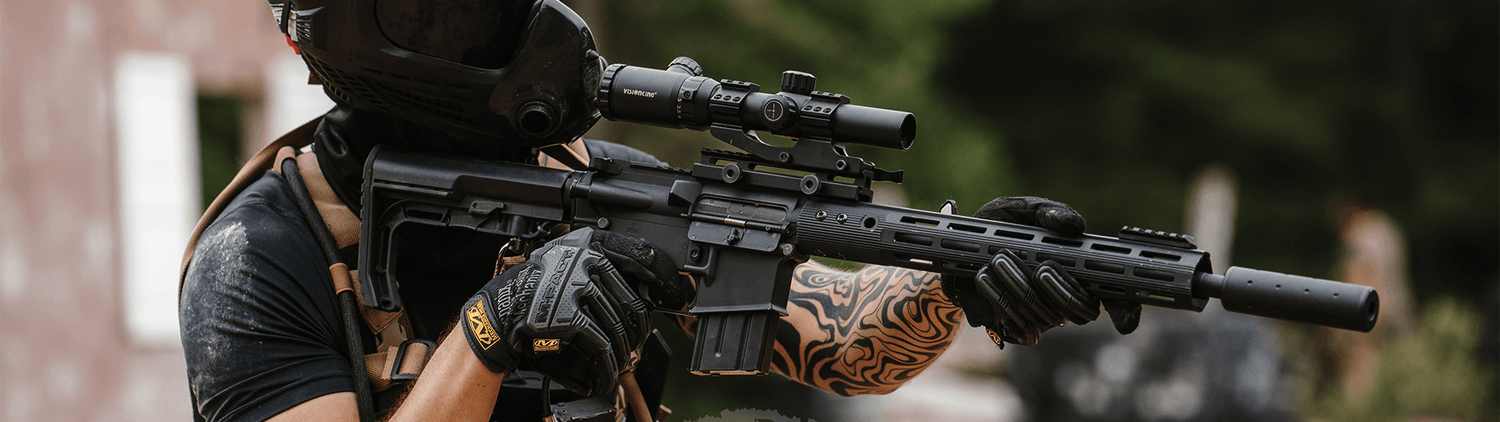 Airsoft DMR replica held by a player wearing tactical gear and aiming outdoors