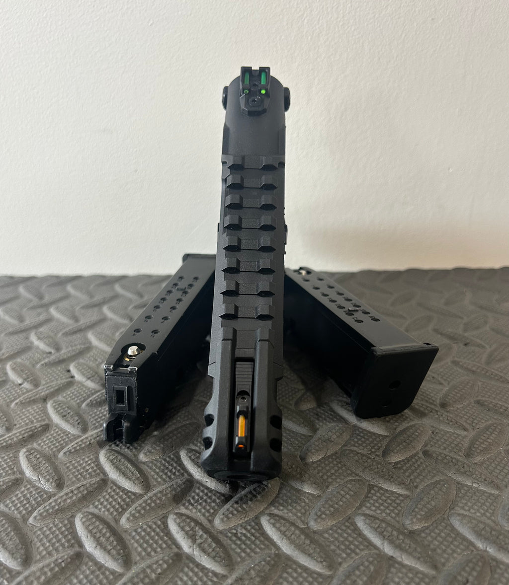 Front view of ACTION ARMY aap-01c assasin airsoft pistol with two magazines on textured surface