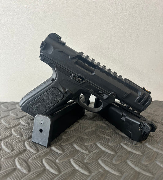 Black ACTION ARMY aap-01c assasin airsoft pistol with two magazines on textured surface