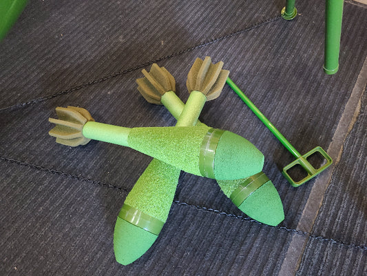 Green foam airsoft mortar rounds with fins and a green metal airsoft mortar stand on carpet