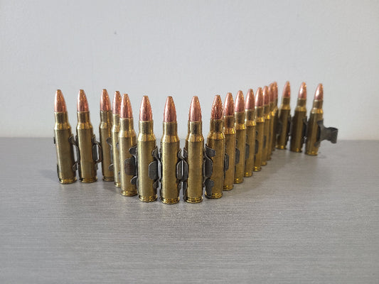 DISTRICT AIRSOFT bullet belt with copper-tipped rounds arranged on gray surface