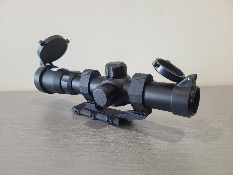 District Airsoft scope 4x24 h18 black rifle accessory with flip-up lens covers on gray surface