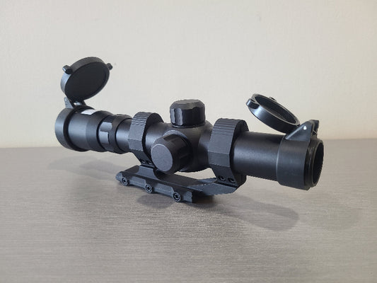 District Airsoft scope 4x24 h18 black rifle accessory with flip-up lens covers on gray surface