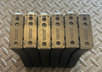 Six Tokyo Marui M4 MWS GBBR magazines stacked on a textured surface for airsoft enthusiasts